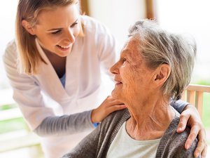 Pflegerin legt Hände auf Schultern der älteren Dame Pflegerin legt Hände auf Schultern der älteren Dame