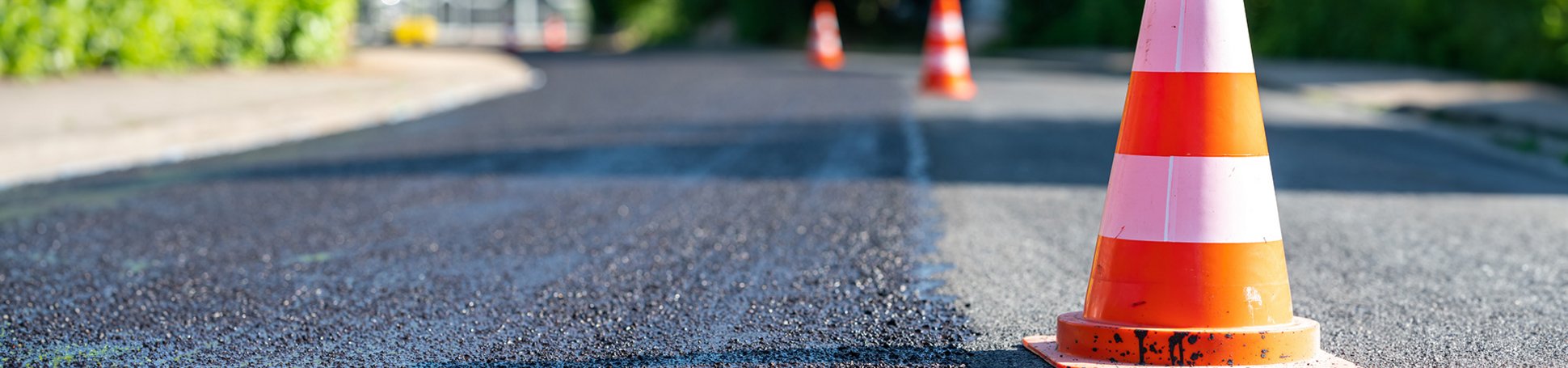 Straße mit Verkehrshütchen und frischem Asphalt