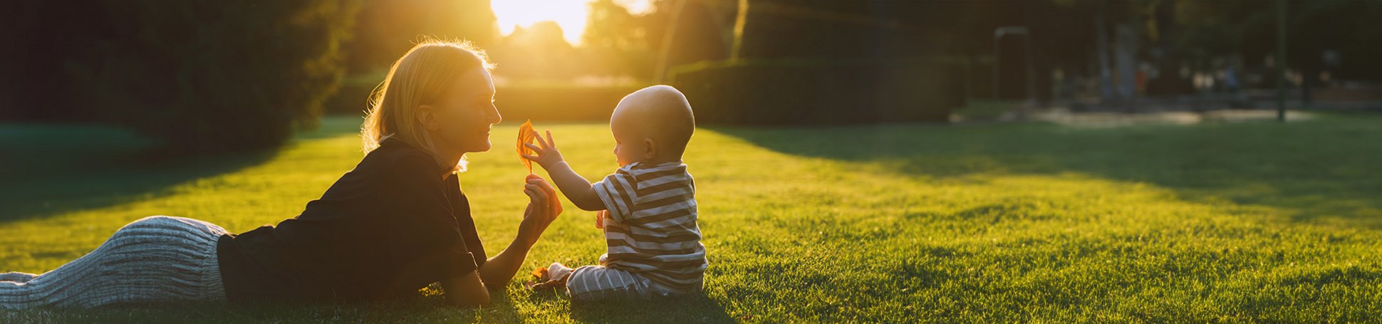 Junge Mutter spielt mit ihrem Baby auf einer Wiese