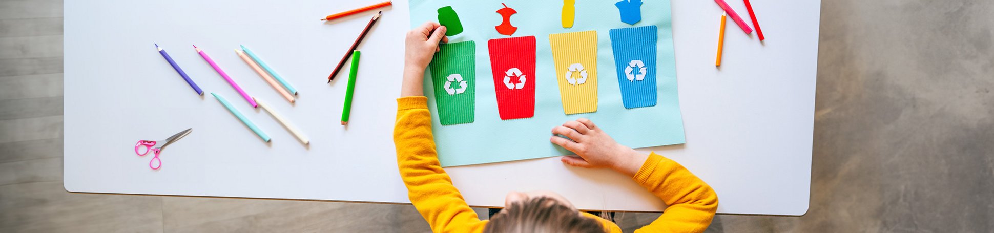Mädchen bastelt verschiedene Mülltonnen auf Papier