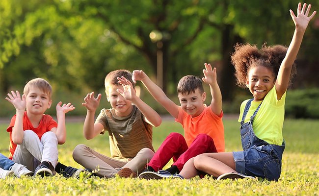 Gruppe von Kindern sitzt auf einer Wiese
