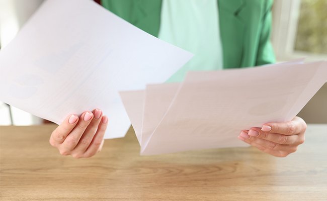 Frau sitzt am Schreibtisch und hälte viele Dokumente