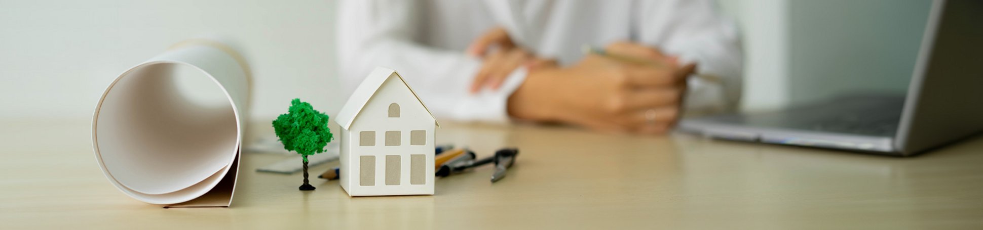Kleines Modellhaus und Arbeitswerkzeug auf einem Büroschreibtisch