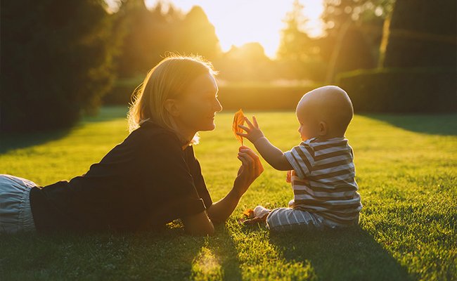 Junge Mutter spielt mit ihrem Baby auf einer Wiese