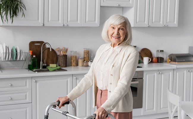 Seniorin läuft mit Rollator durch ihre Wohnung