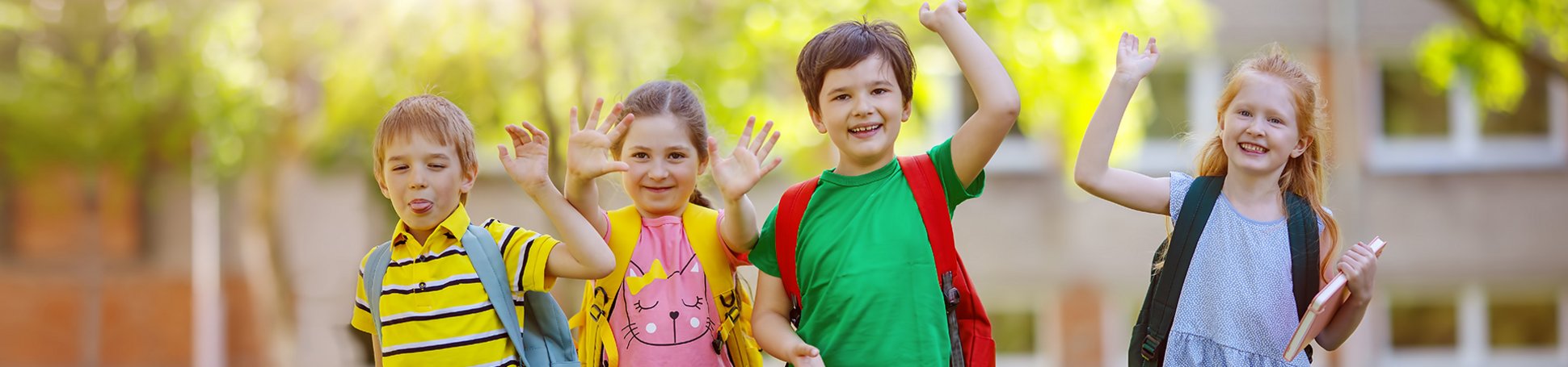 Gruppe von Kindern steht mit Rucksäcken in der Nähe der Schule
