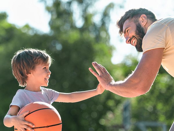 Trainer und Junge klatschen sich beim Basketball ab