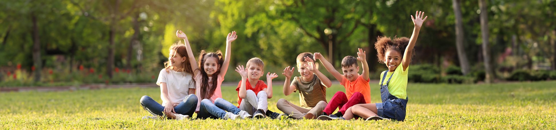 Gruppe von Kindern sitzt auf einer Wiese