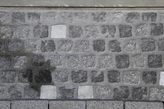 Die Ränder der Pflasterung, also der Bereich zwischen den Gebäudekanten und der Lauffläche, sind mit einem Mosaikpflaster abgesetzt. Die Ränder der Pflasterung, also der Bereich zwischen den Gebäudekanten und der Lauffläche, sind mit einem Mosaikpflaster abgesetzt.
