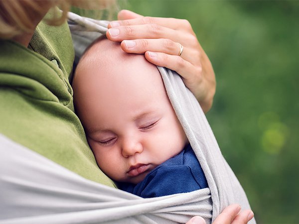  Mutter hält Baby im Tragetuch
