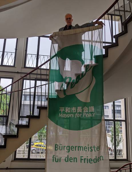 Matthias Müller, Bürgermeister der Stadt Herten, mit der Flagge der Mayors for Peace im Hertener Rathaus.