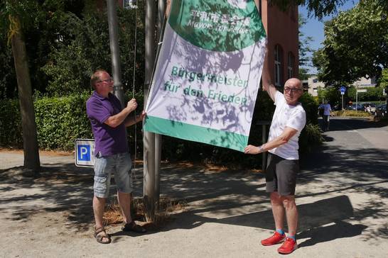 v.l. Slawomir Madarasz (Stadt Herten) und Bürgermeister Fred Toplak hissen die Flagge vor dem Rathaus.