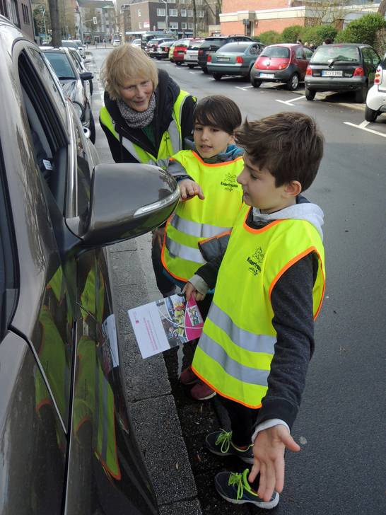 Cüneyt und Julian sprechen Eltern, die ihrer Kinder mit dem Auto abholen, vor der Schule an.
