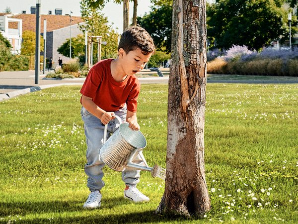 Junge bewässert einen Baum