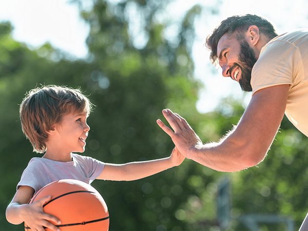 Trainer und Junge klatschen sich beim Basketball ab