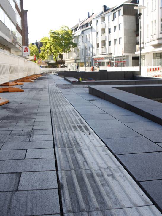 Die neue Gestaltung der oberen Ewaldstraße bindet ebenfalls taktile Elemente ein. Die Leitstreifen am Boden dienen sehbehinderten Menschen zur besseren Orientierung und sollen sie sicher durch die Innenstadt führen. Die neue Gestaltung der oberen Ewaldstraße bindet ebenfalls taktile Elemente ein. Die Leitstreifen am Boden dienen sehbehinderten Menschen zur besseren Orientierung und sollen sie sicher durch die Innenstadt führen.