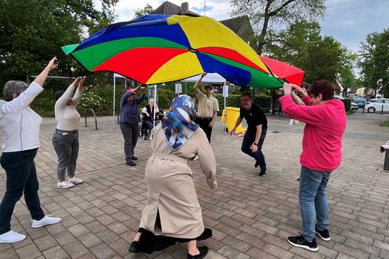 Unterschiedlichste Bewegungsspiele für ältere Menschen bot das Projektteam „Guter Lebensabend“ zusammen mit Pflegelotsinnen und -lotsen am neuen Standort der Wanderbank für Demokratie, Vielfalt und Toleranz am Dorfanger in Bertlich an. Besonders das Schwungtuch kam bei den Seniorinnen und Senioren gut an. (Foto: Stadt Herten).