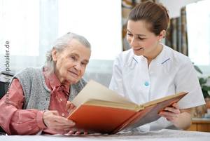 Foto: Weibliche Pflegekraft liest einer Senioren aus einem Buch vor