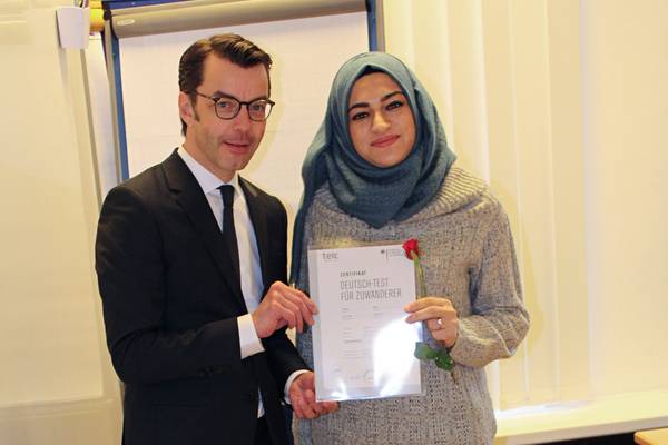Dr. Karsten Schneider, Beigeordneter für Bildung und Soziales, gratuliert Smira Osman zum erfolgreichen Abschluss.