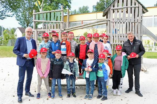 Die Vorschulkinder der Kita „Pusteblume“ in Herten mit den signalroten DEKRA-Kappen. Bürgermeister Matthias Müller (links) und Carsten Debler, Niederlassungsleiter der DEKRA Niederlassung Essen, verteilten die Kappen, damit die Kinder bei ihrem Weg zur Schule sicher sind.