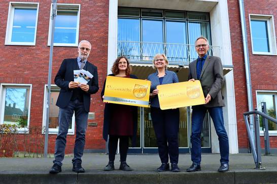 Gemeinsam mit Bürgermeister Matthias Müller (v. l.) zeigen Referentin Stefanie Hasler, Hanna Boßle, städtische Vereinsmanagerin, und Andreas Kersting, Leiter des Referates Bürgerschaftliches Engagement (Staatskanzlei des Landes Nordrhein-Westfalen) vor dem Hertener Rathaus, wie die Ehrenamtskarte - hier in XXL - aussieht.