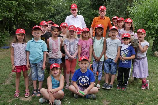 Dekra-Niederlassungsleiter Carsten Debler verteilte gemeinsam mit Bürgermeister Fred Toplak signalrote Sicherheitskappen an die zukünftigen Erstklässlerinnen und Erstklässler des Kindergartens St. Maria Heimsuchung in Herten-Langenbochum.