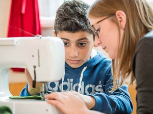 Junge näht mit Nähmaschine