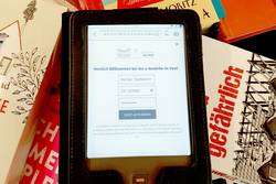 Foto: Ein E-Book-Reader liegt auf mehreren Büchern.