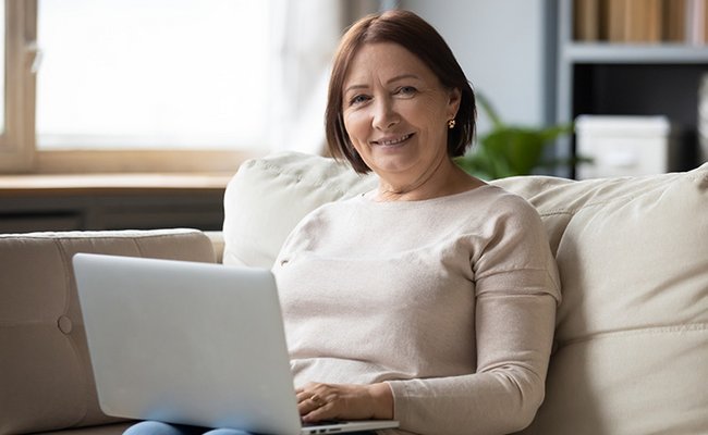 Frau sitzt mit Laptop auf dem Sofa