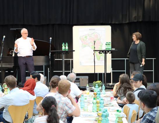 Bürgermeister Matthias Müller zeigt beim Neubürgerempfang den rund 150 Teilnehmenden auf einer Karte sehenswerte Orte in Herten. Rechts im Bild: Moderatorin Stefanie Hasler. Bürgermeister Matthias Müller zeigt beim Neubürgerempfang den rund 150 Teilnehmenden auf einer Karte sehenswerte Orte in Herten. Rechts im Bild: Moderatorin Stefanie Hasler.